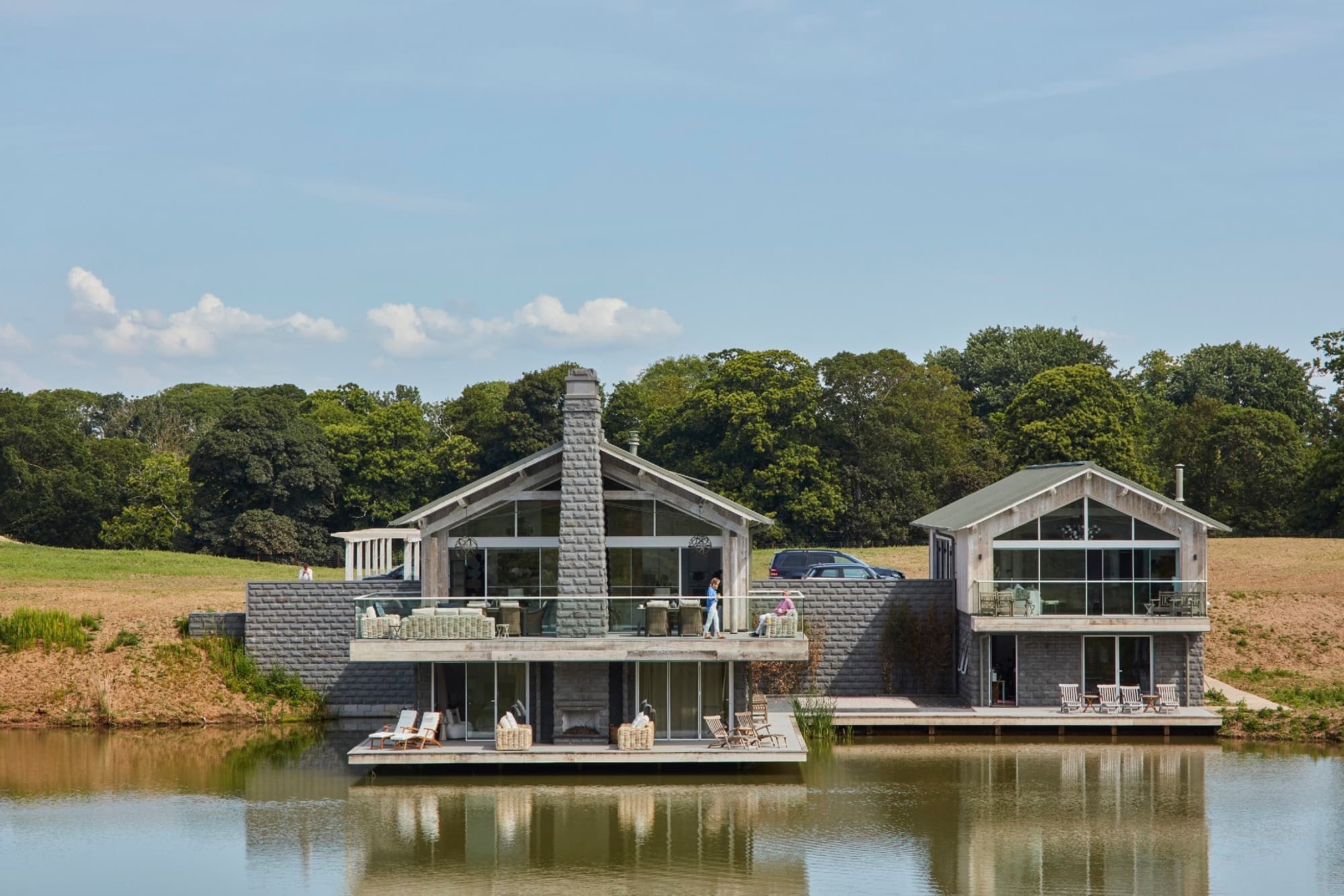 New house on lake with oak cladding, zinc roof and stone external fireplace
